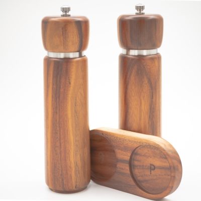 Acacia wood salt and pepper grinders with ceramic grinding cores, displayed on a matching wooden base.