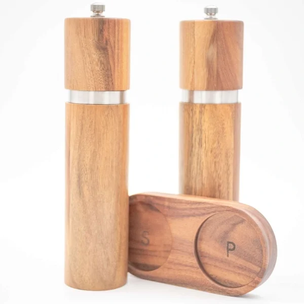 Handcrafted acacia wood salt and pepper grinders with ceramic mechanisms, displayed on a matching wooden tray with natural grain visible.